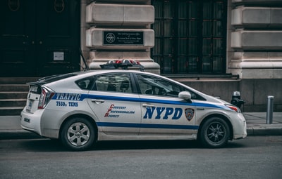 白色丰田普锐斯纽约警察局巡洋舰白天停在混凝土大楼附近